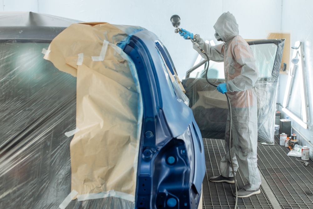 Carrossier ponçant un panneau de carrosserie dans un atelier à Beauharnois