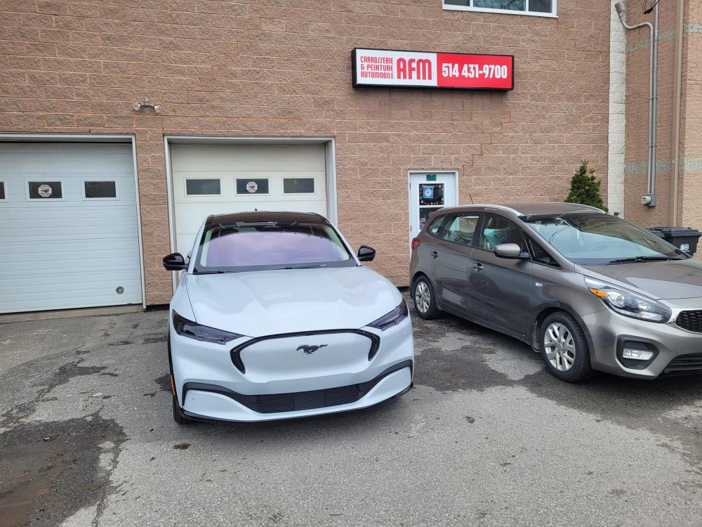  Carrossier ponçant un panneau de carrosserie dans un atelier à L'Île-Perrot 
